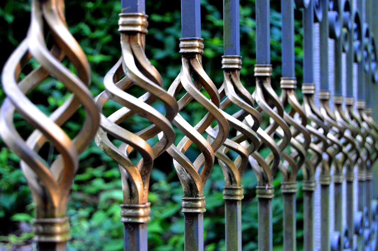 Close view of a black wrought iron gate with early surface rust at a weld
